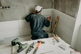 Arbetare reparatör sätter stora keramiska plattor på väggarna